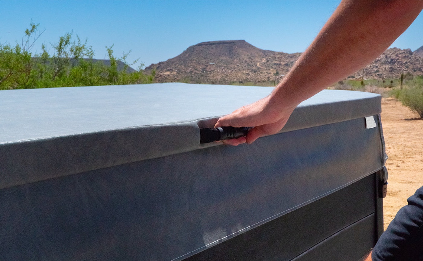 A fitted spa cover being secured on an outdoor hot tub